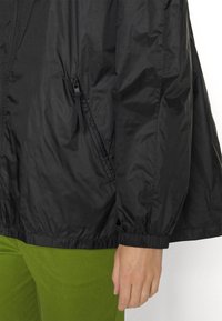 Czarna kurtka typu windbreaker o gładkiej, lekkiej fakturze, z elastycznym dołem i mankietami oraz boczną kieszenią na zamek.