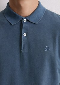 Mørkeblå polo-skjorte i bomull, med klassisk krage, tre knapper og en liten brodert logo på brystet.