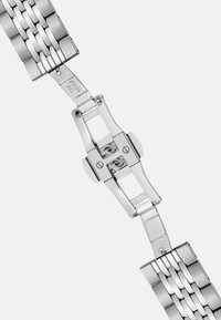 Bracelet de montre en acier inoxydable avec une finition brossée. Présente des maillons entrelacés et un fermoir déployant pour une fermeture sécurisée. Couleur argent.