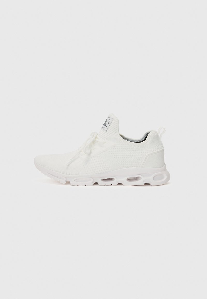 Zapatillas deportivas blancas con un upper de punto texturizado, cordones planos y una suela acolchada con cámaras de aire visibles para mayor soporte.