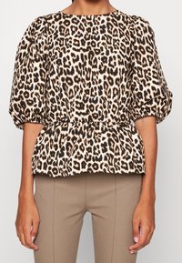 Leopardmönstrad blus med rund halsringning, puffärmar och midjedetalj med volang, tillverkad av ett lätt tyg.