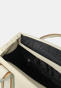Borsa beige con esterno testurizzato, chiusura con zip e fodera interna a motivo con il nome del marchio. Manico in tessuto a righe che accentua la parte superiore.
