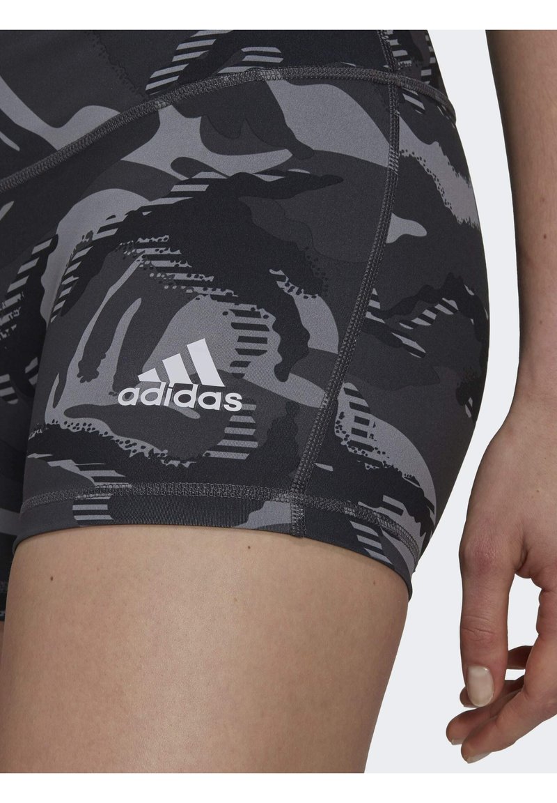Pantalones cortos deportivos de patrón negro y gris, hechos de tela elástica, con un logo de Adidas blanco y costuras en contraste para un detalle adicional.
