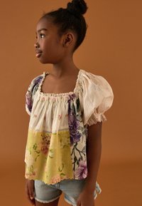 Blusa con motivo floreale e maniche a sbuffo, caratterizzata da uno scollo quadrato e tessuto sovrapposto nei colori crema, giallo e stampe multicolori.