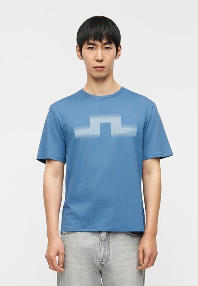 Μπλε βαμβακερό T-shirt με μαλακή υφή, κοντά μανίκια και γεωμετρικό σχέδιο σε ανοιχτό μπλε χρώμα στο στήθος.