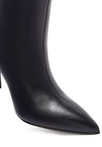 Zwart leren enkelboot met een spitse neus, een slanke textuur en een dunne hoge hak; voorzien van minimale stiksels voor een naadloze uitstraling.