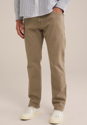 Khakifarbene, gerade geschnittene Hose aus einem weichen, strukturierten Stoff; mit einer Vordertasche und kombiniert mit weißen Sneakers.