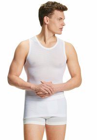 Canotta bianca senza maniche con un design aderente, realizzata in tessuto testurizzato, abbinata a slip boyshort bianchi coordinati. Branding sottile visibile.
