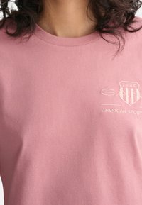 Różowa bawełniana koszulka z okrągłym dekoltem, subtelną teksturą i haftowanym logo z napisem "1949 AMERICAN SPORT."