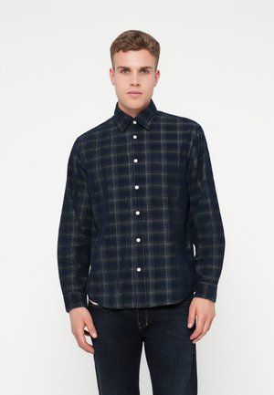 Camisa de botão em padrão de xadrez azul-marinho, feita de algodão, com colarinho clássico, bolso frontal e botões brancos; textura suave e corte ajustado.