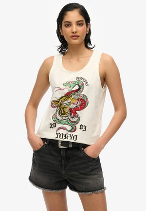 Débardeur blanc avec un graphisme coloré de dragon et de tigre, accompagné du texte "SUPERDRY TOKYO 20". Associé à un short en jean foncé.