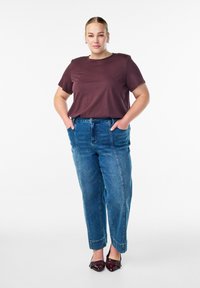 Bordo īsām piedurknēm t-krekls, kombinēts ar augsto vidukli ziliem džinsiem, ar brīvu piegriezumu un sarullētām piedurknēm. Valkāts ar bordo papēžu kurpēm.