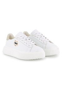 Άσπρα δερμάτινα sneakers με παχύ, ριγέ πάτο. Διαθέτουν ένα παιχνιδιάρικο λογότυπο γάτας με χρυσή λεπτομέρεια στο πλάι και μια λεία, υφή επιφάνεια.