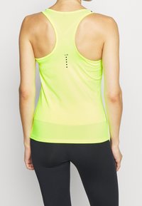 Top atlético amarillo neón con diseño de espalda nadadora, textura suave y puntos decorativos negros en la parte posterior. Ideal para ejercicio y ropa activa.