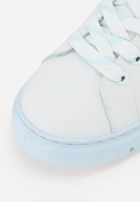 Scarpa da ginnastica sintetica bianca con tomaia liscia, suola in gomma azzurro chiaro e lacci abbinati azzurro chiaro con un delicato motivo a strisce.