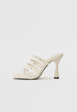 Sandale cu toc înalt crem, cu patru bretele înguste, vârf pătrat, material texturat și toc evazat cu un accent negru.