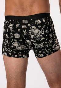 Shorts de boxe noirs avec un imprimé de divers motifs, incluant le Père Noël, des skulls, des instruments de musique et des étoiles.