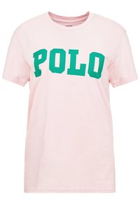 Růžové bavlněné tričko s výrazným, ostrým zeleným potiskem "POLO" na přední straně. Klasický kulatý výstřih a krátké rukávy. Měkká textura.