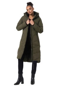 Manteau rembourré long vert olive avec capuche, fermeture éclair à l'avant et poches latérales. Comprend un design matelassé et une coupe légèrement ample.