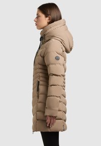 Beżowa kurtka puchowa z regulowanym kapturem, poziomym pikowaniem i czarnymi akcentami zamka błyskawicznego. Posiada emblemat na lewej rękawie.