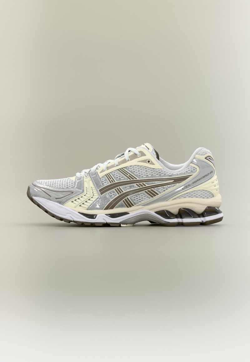 Løbesko i grå og creme med mesh-overdel, hvide snørebånd og polstret sål med et karakteristisk bølgemønster og brune detaljer.