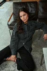 Musta farkkutakki, jossa on koristeita, rento leikkaus, hopean väriset napit ja kaksi rinta-taskua, yhdistettynä leveisiin mustiin housuihin.