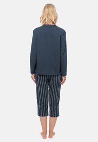 Marineblå langærmet top med rund halsudskæring parret med stribede, cropped pyjamabukser i mørkeblå og hvid. Blødt bomuldsstof.