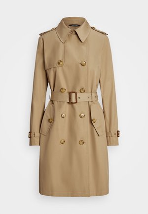Trench-coat beige à double boutonnage avec taille ceinturée, épaulettes boutonnées, poches à rabat et poignets à sangles ajustables, présenté sur fond blanc.