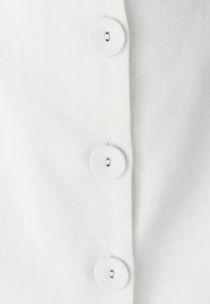 Tessuto bianco con una finitura testurizzata, caratterizzato da tre bottoni rotondi lungo la cucitura. I bottoni sono bianchi con un design a stelo e piccoli fori.