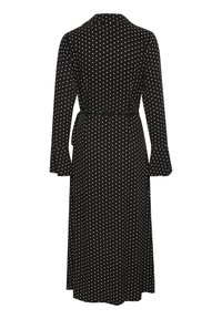 Schwarzes Kleid mit weißen Punkten, langen Ärmeln und tailliertem Bund. Verfügt über einen Kragen und ausgestellte Ärmelbündchen. Glatte Stofftextur.