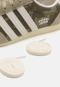 Adidas Japan sneakers in gray suede with a patterned green textile design and three white stripes, accompanied by light beige laces.