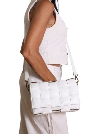 Sac à main tissé blanc de forme rectangulaire structurée. Fabriqué en matériau lisse avec une bandoulière amovible et des accents en métal.