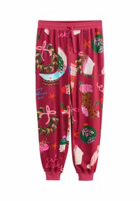 Red jogger pants with Christmas-themed prints including wreaths, stockings, ornaments, polar bears, and festive text, featuring an adjustable drawstring waist.