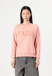 Rózsaszín pulóver, amelyen hímezetten "PARIS" felirat található. Puha anyagból készült, laza szabással, bordázott mandzsettákkal és alsó résszel.