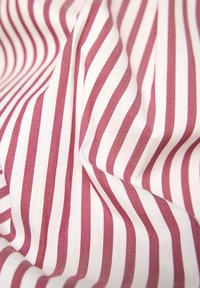 Striped fabric featuring alternating narrow red and white stripes. Texture appears soft with a slight sheen, creating a flowing appearance.