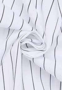 Hvidt stof med smalle sorte striber og subtile metalliske accenter, med en glat tekstur, snoet for at fremvise dets fleksibilitet.