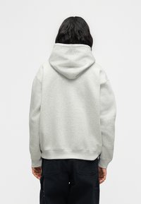 Γκρι φούτερ με fleece ύφασμα, κουκούλα, άνετη εφαρμογή και ριμπ μανσέτες και τελείωμα, φορεμένο με μαύρο παντελόνι cargo. Οπίσθια όψη.