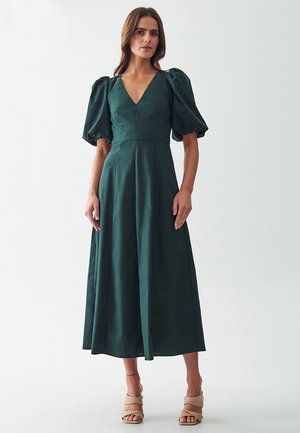 Dark green, knee-length dress with a V-neck and puff sleeves. Fabric appears smooth with a slight sheen. Plain design, no visible patterns.