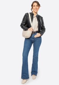 Black leather jacket with studs, striped shirt, blue flared jeans, and beige quilted crossbody bag. Light-colored flat shoes.