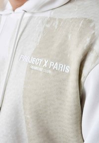 Sudadera con capucha en crema y beige con una superficie texturizada, que presenta los logotipos bordados de "PROJECT X PARIS" y "MEMBERS' CLUB".