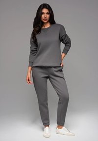 Sudadera gris de mangas largas y cuello redondo, combinada con pantalones jogger grises a juego. Ambos tienen una textura suave y puños elásticos.