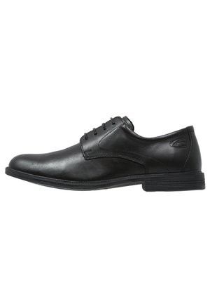 Chaussure habillée pour homme en cuir noir avec fermeture à lacets et un petit talon empilé, vue de profil sur fond blanc.