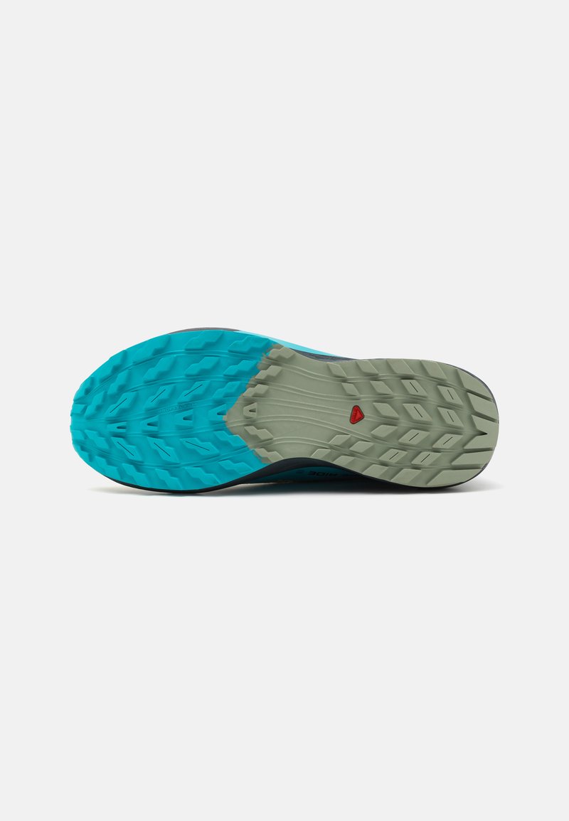 Suela de zapato con un diseño azul y gris, con patrones de textura en la banda de rodadura que incluyen formas en zigzag y acentos circulares para mejorar la tracción.