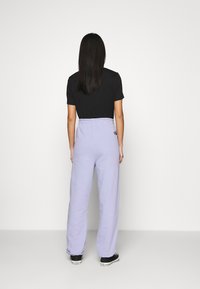 Fialové tepláky s volným střihem, s elastickým pasem a černými akcenty, spárované s přiléhavým černým tričkem.