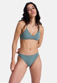 Ensemble bikini vert en matière lisse, comprenant un haut triangulaire et un bas taille basse. Design simple avec fines bretelles et sans ornements.