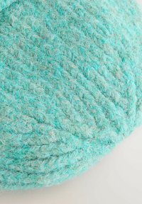 Megzta turkio spalvos vilnos audinys su švelniu, tekstūruotu paviršiumi, kuriame matomas persipynusių siūlų raštas ir švelnus blizgesys.