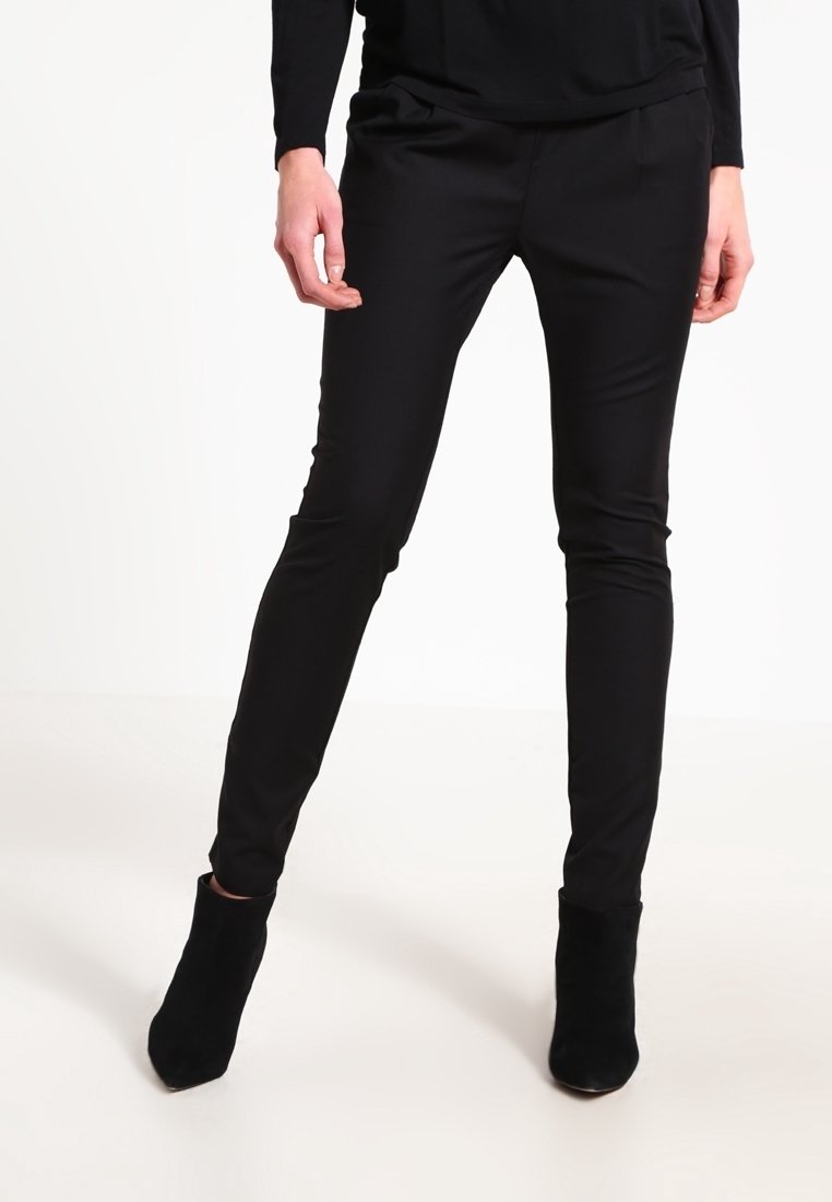 Svarta tapered byxor i slät tyg, med en stilren design, medelhög midja och sidofickor, matchade med svarta ankelboots.