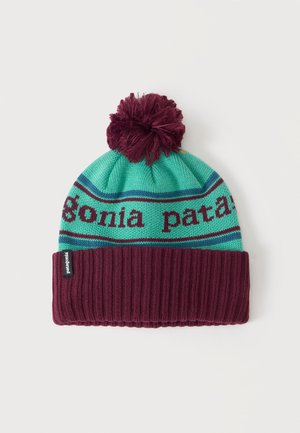 Megzta kepurė su žalsvai mėlynomis ir bordo juostelėmis, bordo spalvos bumbulas viršuje, ribota apykaklė ir Patagonia logotipo žymė ant apykaklės.