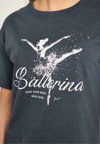 Mørkegrå bomuld t-shirt med en hvid og lyserød ballerina grafik samt teksten "Ballerina" og "Hold dit hoved højt."