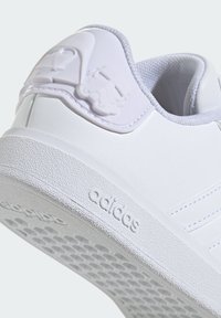 Baskets blanches avec semelle en caoutchouc texturé, présentant des accents moulés de Dark Vador et d'un stormtrooper sur le talon. Marque adidas sur le côté.